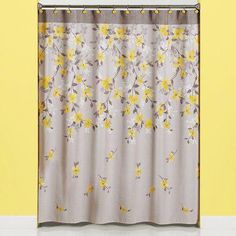 a shower curtain with yellow flowers on it in front of a yellow wall and white floor