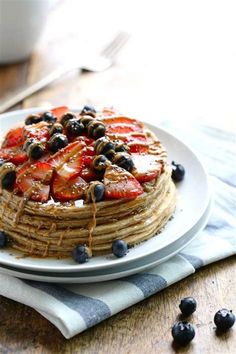 a stack of pancakes with blueberries and strawberries on top