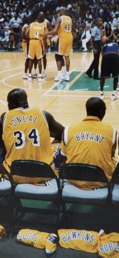 three basketball players sitting on the sidelines during a game with their numbers printed on them