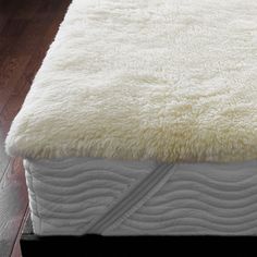 a close up of a mattress on a wooden floor with a white blanket and wood floors