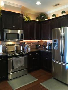 a kitchen with stainless steel appliances and dark wood cabinets