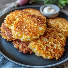 three pancakes on a black plate with some dipping sauce