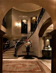 an elegant entry way with flowers in a vase on the table and stairs leading up to it