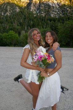 two beautiful young women standing next to each other holding bouquets of flowers in their hands