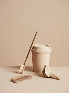 a cup with a toothbrush next to it and a comb on the table in front of it