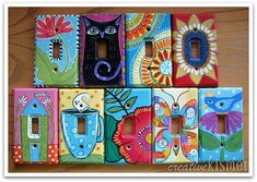 some colorful painted light switch plates on a wooden table with flowers and cats in them