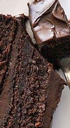 a piece of chocolate cake sitting on top of a white plate next to a fork