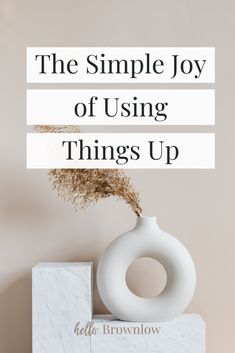 a white vase sitting on top of a marble block next to a sign that says the simple joy of using things up