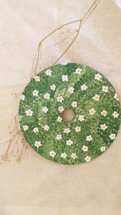 a green plate with white daisies on it sitting on top of a cloth covered tablecloth