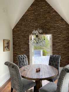 a dining room table with grey chairs and a chandelier hanging from the ceiling