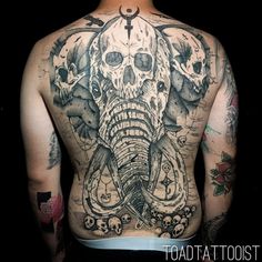 a man with tattoos on his back has an elephant and skulls tattoo on it's back