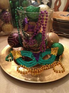 a gold plate topped with beads and mardi gras mask sitting on top of a table