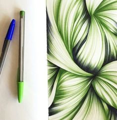 a green and white flower drawn on paper next to a pen