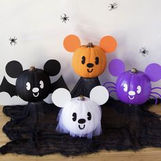 three halloween pumpkins with mickey mouse heads and ghost faces on them, sitting in front of a white wall