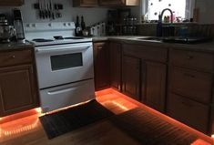 a kitchen with wooden cabinets and white stove top oven in the center, illuminated by red lights