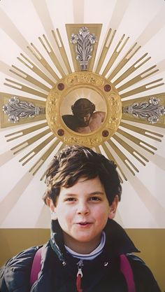 a young boy standing in front of a cross with the image of jesus on it