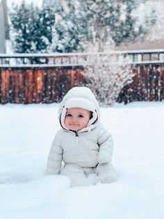 a baby sitting in the snow wearing a hat