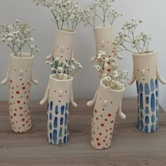 four ceramic vases with flowers in them on a table