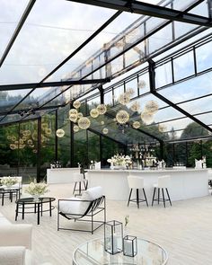 an outdoor bar with chairs and tables in the middle is decorated with chandeliers