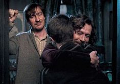 two men hug each other in front of a mirror while another man looks at them