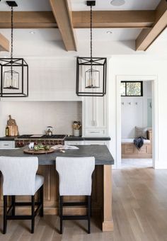 a kitchen island with two stools next to it and some lights hanging from the ceiling