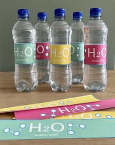 four bottled water bottles sitting on top of a table next to a sign that says h2o