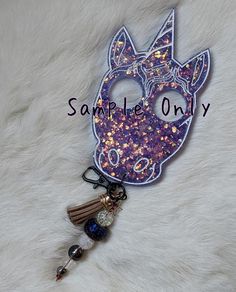 a purple mask keychain with a tassel hanging from it's side