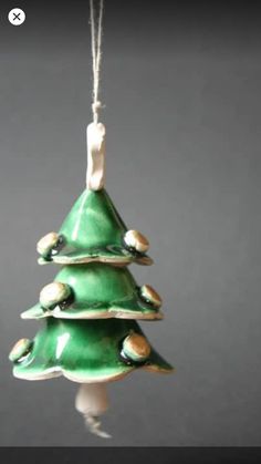 a green ceramic christmas tree ornament hanging from a string