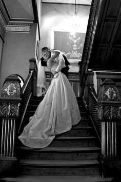 a bride and groom are kissing on the stairs at their wedding reception in black and white