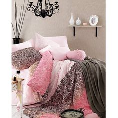 a bed covered in pink and brown comforter next to a black chandelier