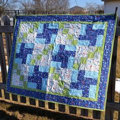 a blue and green quilt hanging on a fence