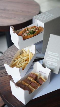 three takeout boxes filled with food sitting on top of a table next to each other