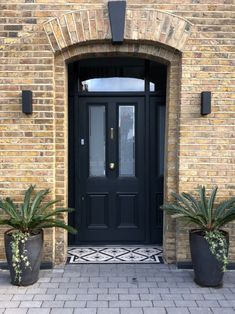 a black door with two planters in front of it