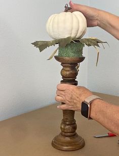 an old woman is holding a pumpkin on top of a candle holder that has been turned into a vase