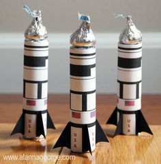 three small rockets sitting on top of a wooden table