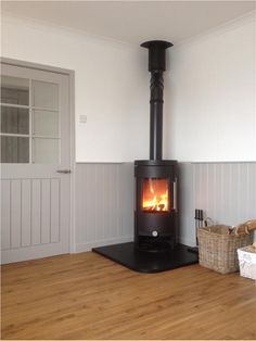 a wood burning stove in the corner of a room with white walls and wooden floors