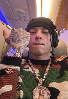 a man with headphones on his ears is sitting in an airplane and has tattoos on his arm