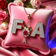 a pink pillow with the word fa on it and flowers in front of it, sitting next to a bouquet of roses