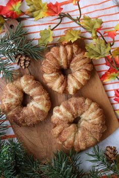 three bundt cakes sitting on top of a wooden cutting board next to pine cones