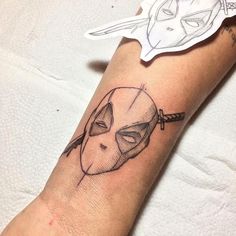 a person's arm with a tattoo on it that has a mask and arrow