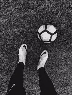 a person is standing in front of a soccer ball on the ground with their feet up