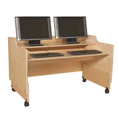 two computer monitors sitting on top of a wooden desk