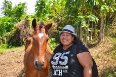 a woman standing next to a brown horse