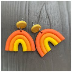 two pairs of orange and yellow earrings on top of a wooden table