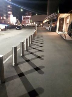 a row of metal poles sitting on the side of a road next to a parking lot