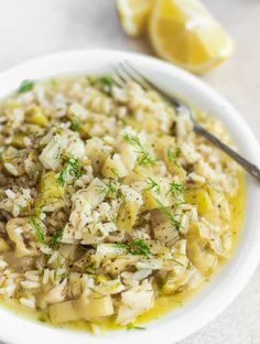 a white bowl filled with rice and lemons on top of a table next to a fork