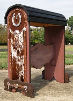 a wooden bench with a cow hide in the middle and a saddle on it's back