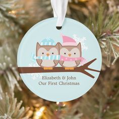 an ornament with two owls sitting on a branch in front of a christmas tree