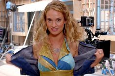 a woman in a blue and gold dress is holding her jacket open while posing for the camera