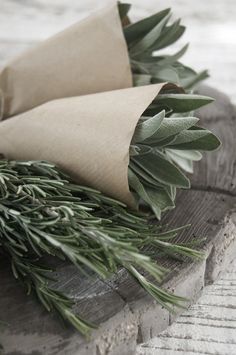 some green leaves are laying on top of a piece of wood and wrapped in brown paper